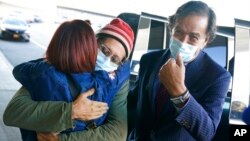 Danny Fenster, center, hugs his mother Rose Fenster as former U.S. diplomat Bill Richardson, right, looks on at John F. Kennedy Airport in New York, Nov. 16, 2021. 