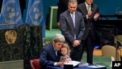 美国国务卿克里手臂中搂着他的孙女在联合国总部签署巴黎气候协议。（2016年4月22日）