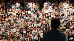 Désirée Bouchat, a survivor of the 9/11 attacks on the World Trade Center, looks at photos of those who perished, in a display at the 9/11 Tribute Museum, Friday, Aug. 6, 2021, in New York.