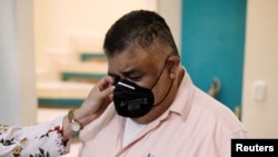 Erwin Pozuelos, quien posee una escuela técnica con su esposa Aura Cartagena, reacciona mientras ella ajusta su mascarilla cuando está de pie en su casa, que pusieron a la venta, durante la pandemia de la enfermedad por coronavirus, en Ciudad de Guatemala, 18 de agosto de 2020.