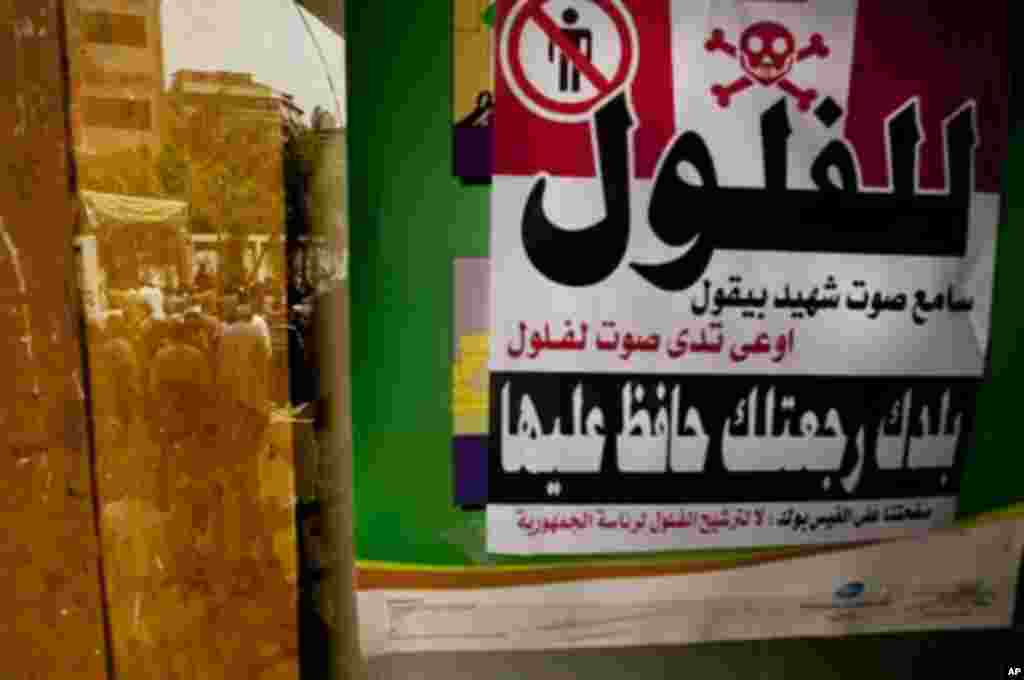 Egyptian voters are reflected in a window where a sign hangs reading "No to 'feloul' (remnants of the old regime). I hear the martyrs calling don't vote for a 'feloul,'" in Maadi, a southern suburb of Cario, Egypt on Wednesday, May 23, 2012. On Wednesday