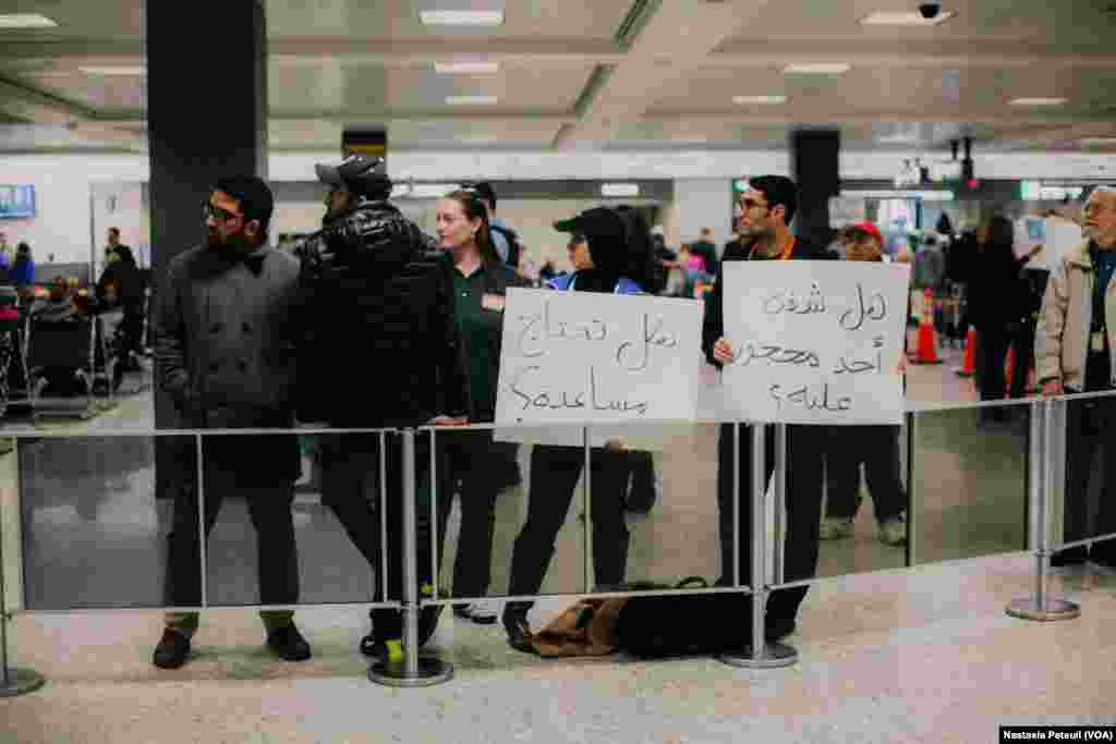 Des bénévoles tiennent des pancartes écrites en arabe "Avez-vous été détenu ?" à l'aéroport international de Washington DC, le 31 janvier 2017. (VOA/Nastasia Peteuil)