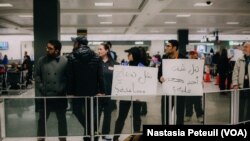 Des bénévoles tiennent des pancartes écrites en arabe "Avez-vous été détenu ?" à l'aéroport international de Washington DC, le 31 janvier 2017. (VOA/Nastasia Peteuil)