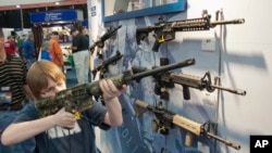 Un jeune homme essaie une arme pendant la convention annuelle de la National Rifle Association, à Houston, en 2013. (AP Photo/Steve Ueckert)