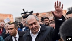 Armenian president Armen Sarkissian greets demonstrators in the Republic Square gathered to protest the former president's shift into the prime minister's seat in Yerevan, Armenia, April 21, 2018. 