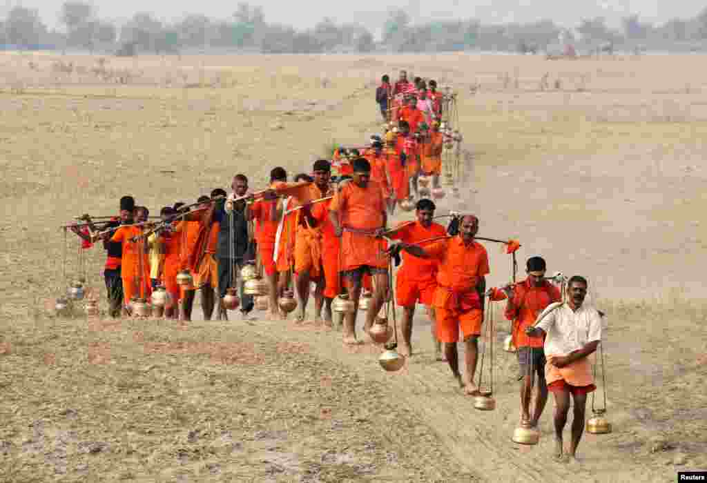 Para penganut Hindu, Kanwariyas, membawa bejana berisi air suci setelah sebelumnya melakukan ritual mandi suci di Sungai Ganga, di Allahabad, India.