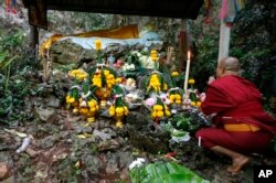 FILE - A Thai Buddhist monk prays for 12 boys and their soccer coach, in Mae Sai, Chiang Rai province, northern Thailand, June 27, 2018.