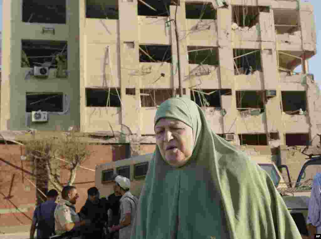 An Egyptian woman walks near the damaged national security building after a bomb exploded early in the Shubra el-Kheima neighborhood of Cairo, Aug. 20, 2015.