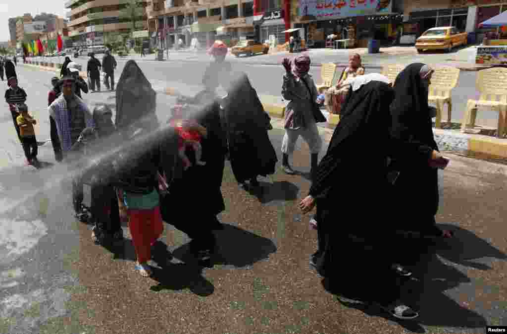 A resident sprays water as he cools off Shi'ite pilgrims in Baghdad, Iraq, June 13, 2012.