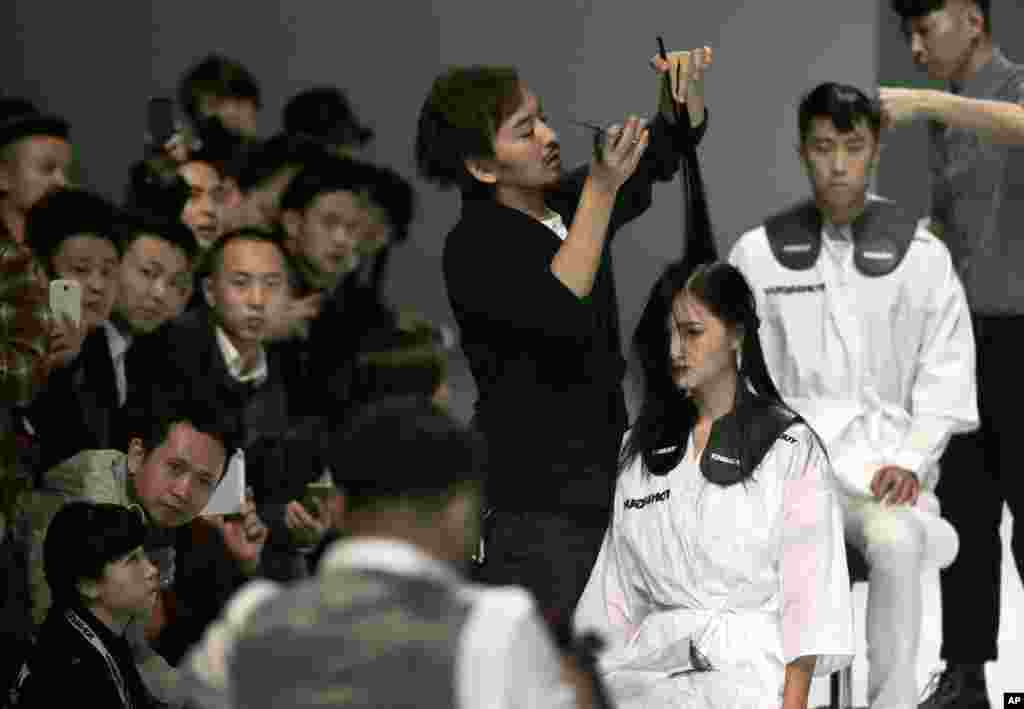 Hairstylists demonstrate their hair cutting skills on models' hair on the catwalk during a showcase of Toni & Guy 2015 Hairstyling Trends collection at China Fashion Week in Beijing.