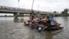 Sekelompok migran Amerika Tengah menyeberangi Sungai Suchiate di atas rakit yang terbuat dari ban dalam traktor dan papan kayu, di perbatasan antara Guatemala dan Meksiko, Ciudad Hidalgo, Meksiko, Sabtu, 20 Oktober 2018. (Foto: dok).