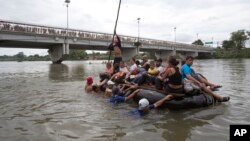 Sekelompok migran Amerika Tengah menyeberangi Sungai Suchiate di atas rakit yang terbuat dari ban dalam traktor dan papan kayu, di perbatasan antara Guatemala dan Meksiko, Ciudad Hidalgo, Meksiko, Sabtu, 20 Oktober 2018. (Foto: dok).