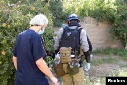 FILE - A U.N. chemical weapons expert (R) gathers evidence at one of the sites of an alleged poison gas attack in the southwestern Damascus suburb of Mouadamiya, Aug. 26, 2013.