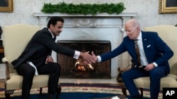 President Joe Biden, right, shakes hands with the Qatar's Emir Sheikh Tamim bin Hamad Al Thani in the Oval Office of the White House, Jan. 31, 2022, in Washington. 