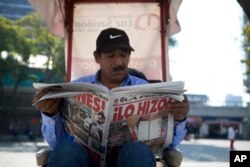 A man having his shoes shines reads a newspaper whose front page declares "He did it!" over a picture of U.S. President Donald Trump holding up signed documents, as he took action to jumpstart construction on a promised border wall, in Mexico City, Jan. 26, 2017.