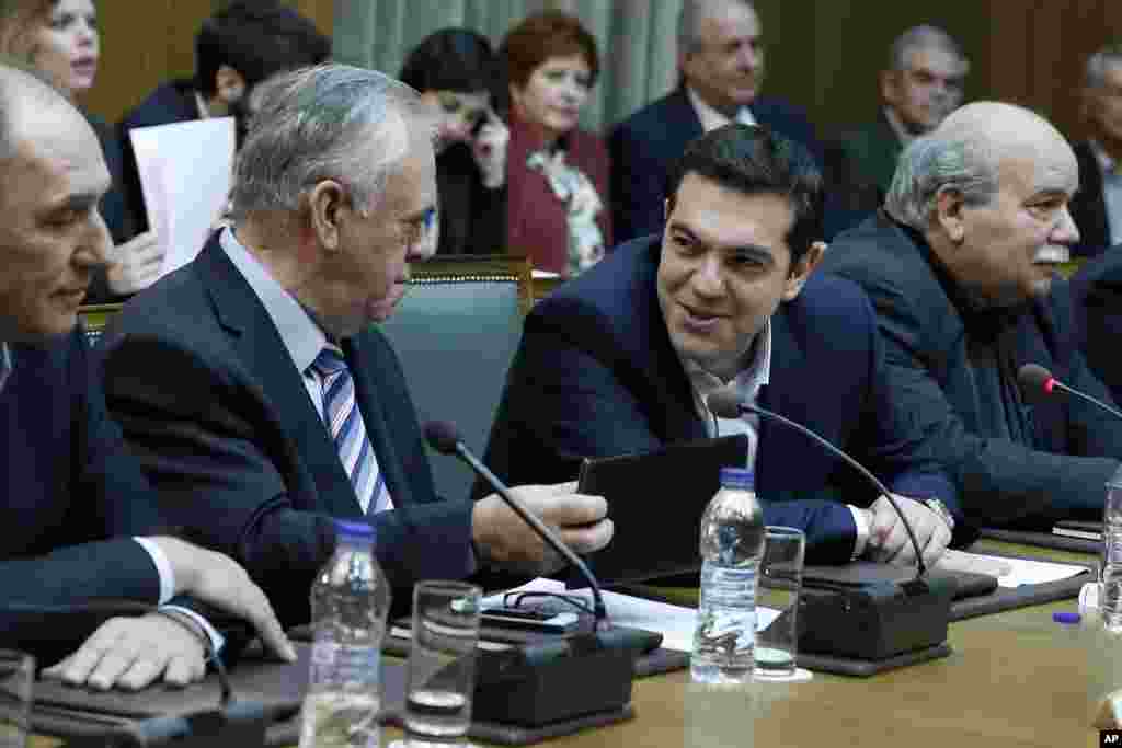 Prime Minister Alexis Tsipras (2nd right) and Deputy Prime Minister Giannis Dragasakis chat during the first cabinet meeting of the new government at the Parliament in Athens, Jan. 28, 2015.