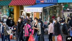 FILE - In this March 30, 2021, file photo, people cross a busy street in the shopping district of Flushing, a largely Asian American neighborhood in the Queens borough of New York. (AP Photo/Kathy Willens, File)