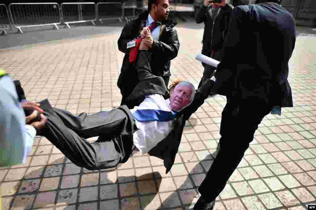 Security guards carry a protester wearing a mask depicting Sir David Walker, outgoing Chairman of Barclays Bank, during a demonstration outside the bank&#39;s annual general meeting (AGM) in London, April 22, 2015.