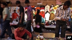 Indians walks past roadside stalls selling clothes and miscellaneous items in New Delhi, India. Indian Finance Minister, Mukherjee, presented India's new budget amid concerns about inflation, the country's falling growth rate, large deficit, FILE March 16