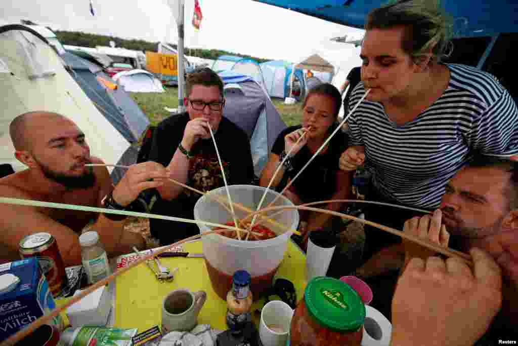 Festival goers from the north-eastern German city of Greifswald use straws to drink from a self-mixed brew of fruits, juice, wine and booze during drinking games at a camp site for&nbsp; the world&#39;s largest heavy metal festival, the Wacken Open Air 2019, in Wacken, Germany.