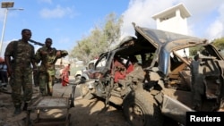 FILE - Somali police gather at the wreckage of a car following a bombing in the capital city of Mogadishu, March 9, 2016. Government officials have proposed a new electoral process to help quell violence in the country. 