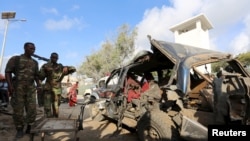 Somali policemen look at the wreckage of a car at the scene of an explosion following an attack in Somalia's capital Mogadishu, March 9, 2016. 