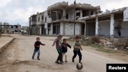 Children play near damaged buildings in the rebel-held southern town of Bosra al-Sham, Deraa, Syria, Feb. 23, 2016. Negotiations continue on a proposed cease-fire.