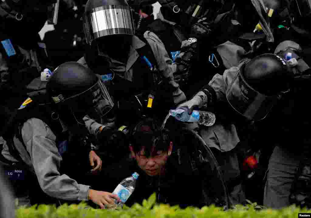 Riot police pour water on the face of an anti-government protester who was pepper sprayed while getting detained after an anti-parallel trading protest at Sheung Shui, a border town in Hong Kong.