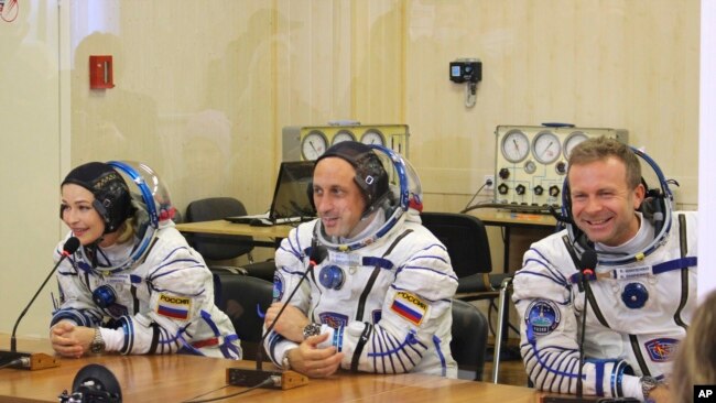 Actress Yulia Peresild, left, film director Klim Shipenko, right, and cosmonaut Anton Shkaplerov speak with their relatives through a safety glass prior the launch at the Baikonur Cosmodrome, Kazakhstan, Oct. 5, 2021.