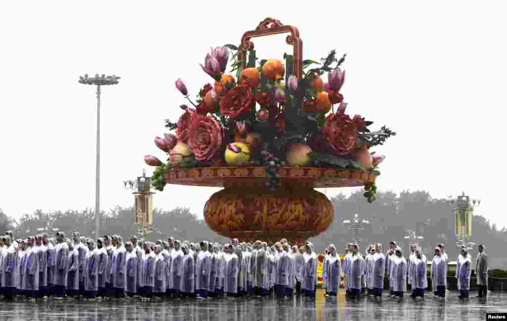 Para mahasiswa mengenakan jas hujan menunggu upacara penghormatan di Monumen Pahlawan Rakyat di Lapangan Tiananmen, Beijing, China,.