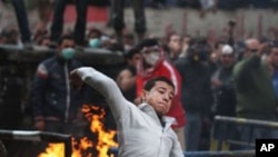 An Egyptian protester throws rocks toward Egyptian riot police in Cairo, Egypt, Monday, Nov. 21, 2011. Security forces fired tear gas and clashed Monday with several thousand protesters in Cairo's Tahrir Square in the third straight day of violence that h