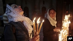 A worshiper holds candles as she prays inside the church of Holy Sepulcher in Jerusalem's Old City, April 24, 2011