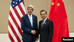 美國國務卿克里(左）和中國外長王毅（右）在東盟外長會議上會面握手。