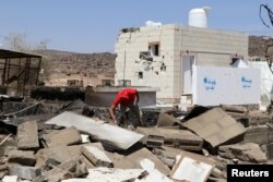 FILE - An aid worker searches the wreckage at the scene of an air strike that hit a gas station near a hospital in Kutaf district of the northwestern province of Saada, Yemen, March 28, 2019.