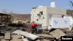 FILE - An aid worker searches the wreckage at the scene of an air strike that hit a gas station near a hospital in Kutaf district of the northwestern province of Saada, Yemen, March 28, 2019. 