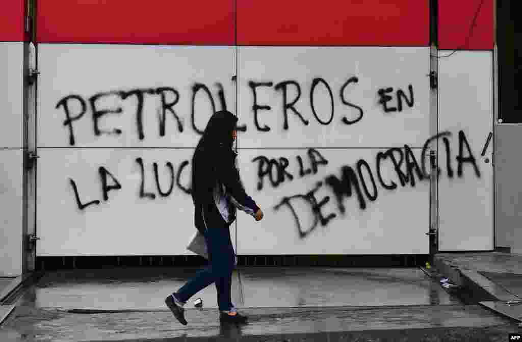 Muchos bolivianos salieron a las calles a celebrar la renuncia del expresidente Evo Morales. Consideran que, a partir de ahora, se podría abrir una nueva etapa en el país y ven con optimismo el rumbo político. En esta imagen, una mujer camina frente a una pintada que dice &quot;Petroleros en la lucha por la democracia&quot; en La Paz (Bolivia).&nbsp;La Organización de Estados Americanos (OEA) había recomendado la anulación de los comicios celebrados el 20 de octubre porque, tras una extensa auditoría, se habían detectado ciertas irregularidades en el proceso. Por eso, la organización internacional reclamó un proceso mucho más transparente.