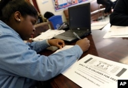FILE - Akira Lee, a senior at Roosevelt High School, fills out a college enrollment application at her school in Washington.