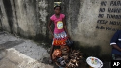 Twelve-year-old, Kemi Olajuwon, who has to drop out of school some days to sell smoked fish and make money so there can be food in the house, and also for her school fees, displays her fish on the street in the Obalende area of Lagos, Nigeria, Tuesday, June 17, 2014.