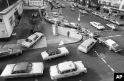 FILE - Cars line up in two directions at a gas station during fuel shortages brought about by an Arab oil embargo, in New York City, Dec. 23, 1973. The embargo was among the factors that pushed the U.S. government to pursue greater vehicle fuel efficiency.