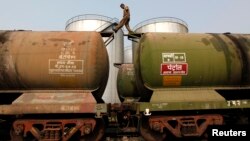 FILE - A worker walks atop a tanker wagon to check the freight level at an oil terminal on the outskirts of Kolkata, Nov. 27, 2013. 
