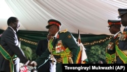 FILE: The Commander of the Defence Forces, Constatine Chiwenga, centre, congratulates President Robert Mugabe, left, as other military officers look on, during the inauguration ceremony of President Mugabe, at State House in Harare, Zimbabwe, Sunday.
