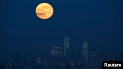 A full moon is seen in the sky behind New York's Lower Manhattan skyline in this June 23, 2013, file photo.