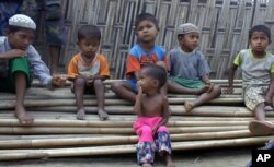 FILE - In this March 17, 2017, image made from video, Rosmaida Bibi, center foreground, suffering from severe malnutrition, sits on a pile of bamboo trees with other children at the Dar Paing camp, north of Sittwe, Rakhine state, Myanmar.