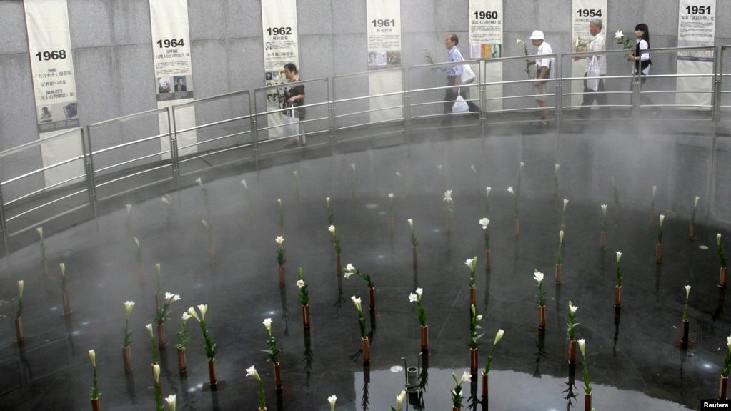 资料照片：“白色恐怖”受难者亲属在台北举行的一次纪念解除戒严22周年的仪式期间手持百合花走过一个布满百合花的水池。(2009年7月15日)