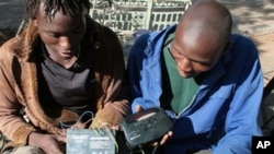 FILE - Two men listen to a battery-operated radio for results of the country's 2008 elections, in Bulawayo, Zimbabwe.
