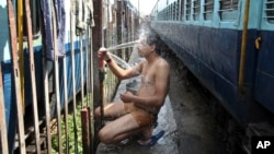An Indian passenger takes a bath beside rail tracks on a hot summer day at a railway station in Jammu, India, Monday, May 25, 2015. Severe heat wave conditions continue to prevail at several places in northern India with temperatures reaching 48 degrees C