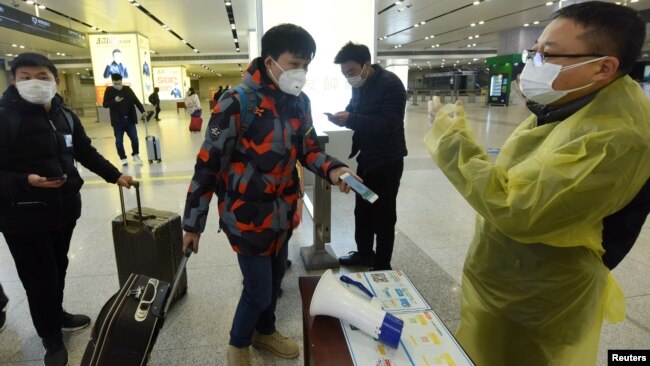 中国浙江省杭州市火车站一名旅客使用手机中的绿色健康码向车站检疫人员显示他的健康状况。(2020年2月17日)