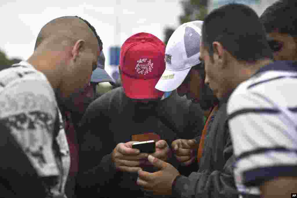 Para pengungsi mengecek peta di ponselnya saat mereka berjalan ke arah Austria, Budapest, Hungaria (5/9). (AP/Marko Drobnjakovic)
