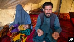 FILE - Mohammad Azam, whose pregnant teenage daughter Zarah died after being set on fire in her husband’s home, speaks about her death while an unidentified woman and child rest nearby in Kabul, Afghanistan, July 18, 2016. Azam traveled to the capital to call for justice.