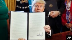 President Donald Trump holds up an executive order in the Oval Office of the White House, Feb. 3, 2017. The executive order will direct the Treasury secretary to review the 2010 Dodd-Frank financial oversight law.